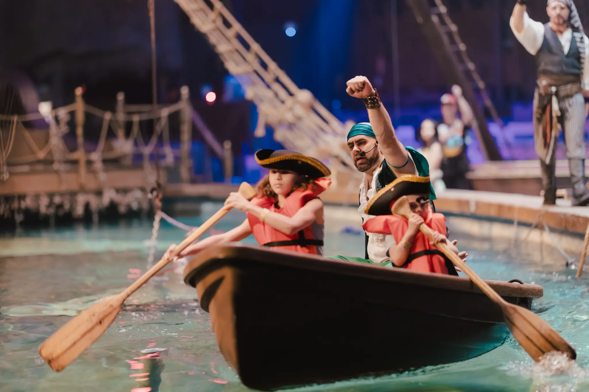Children and performers competing in a boat race on the show floor