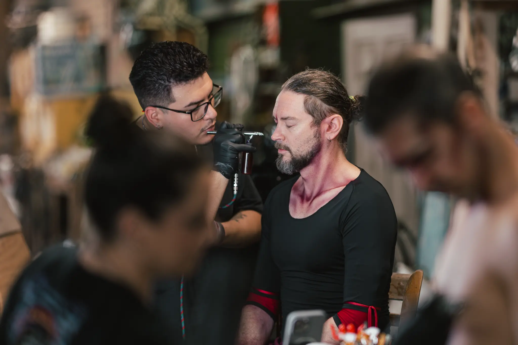 Cast member receiving airbrush make-up behind the scenes