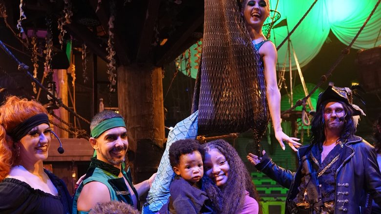 Cast members celebrate on stage with a guest family after the show