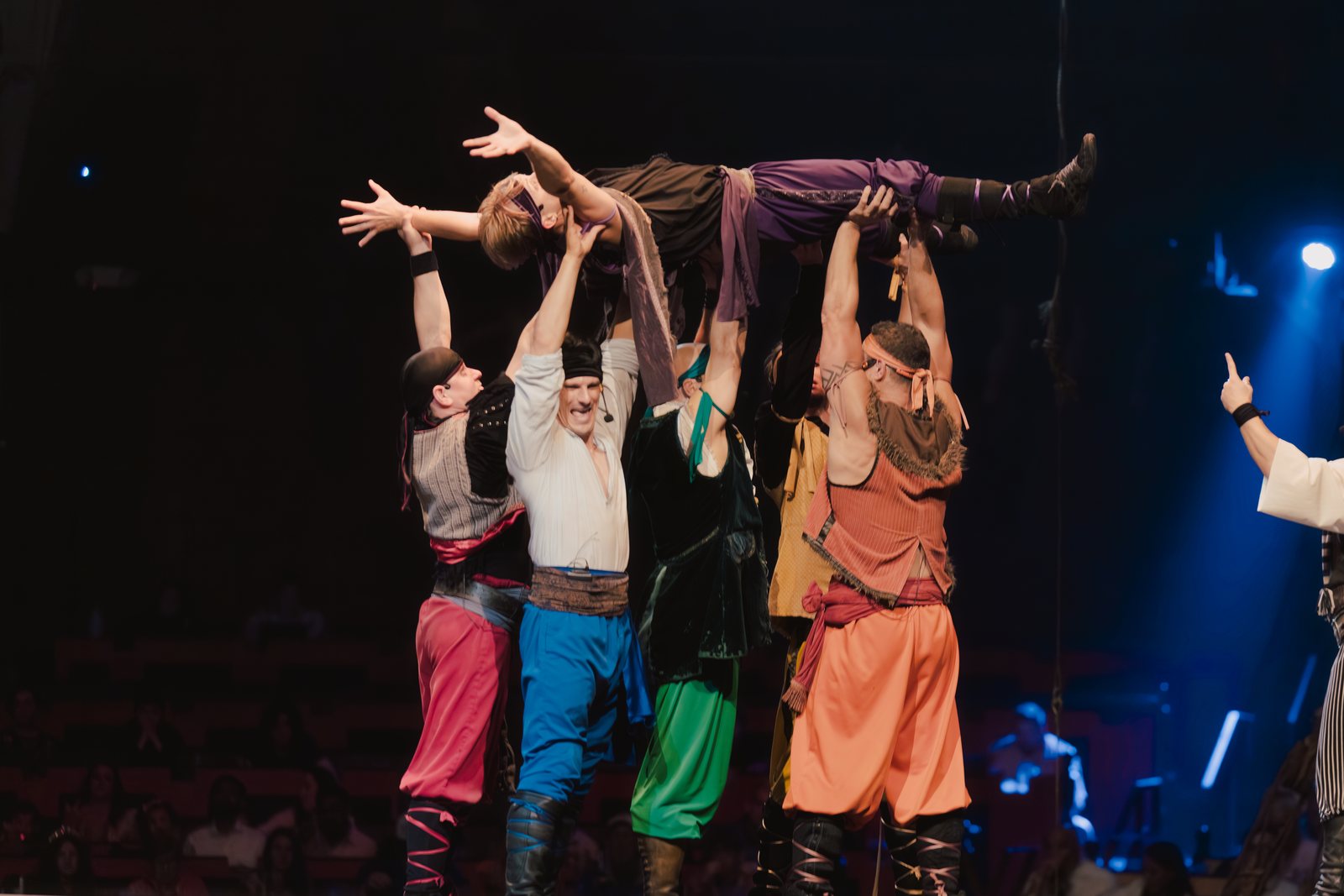 Pirate performers hoist an acrobat overhead during a live stunt
