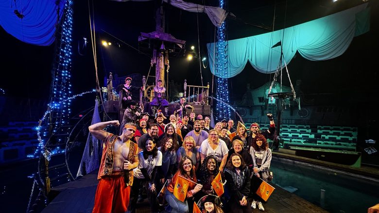 A large group of guests gathers on the ship set with the full pirate cast